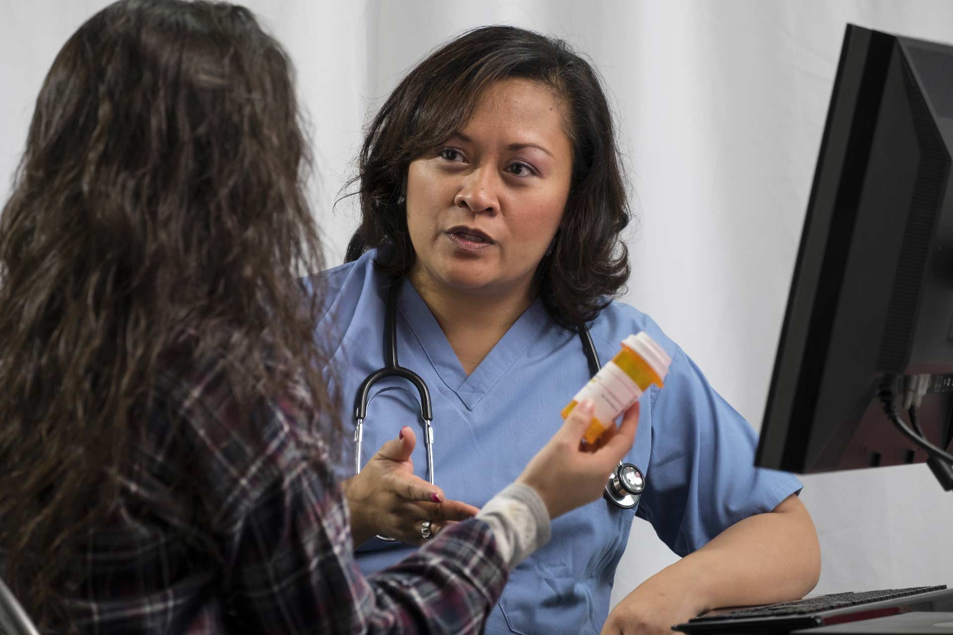 Cannabis nurse explains medication interactions to a woman holding a prescription bottle.