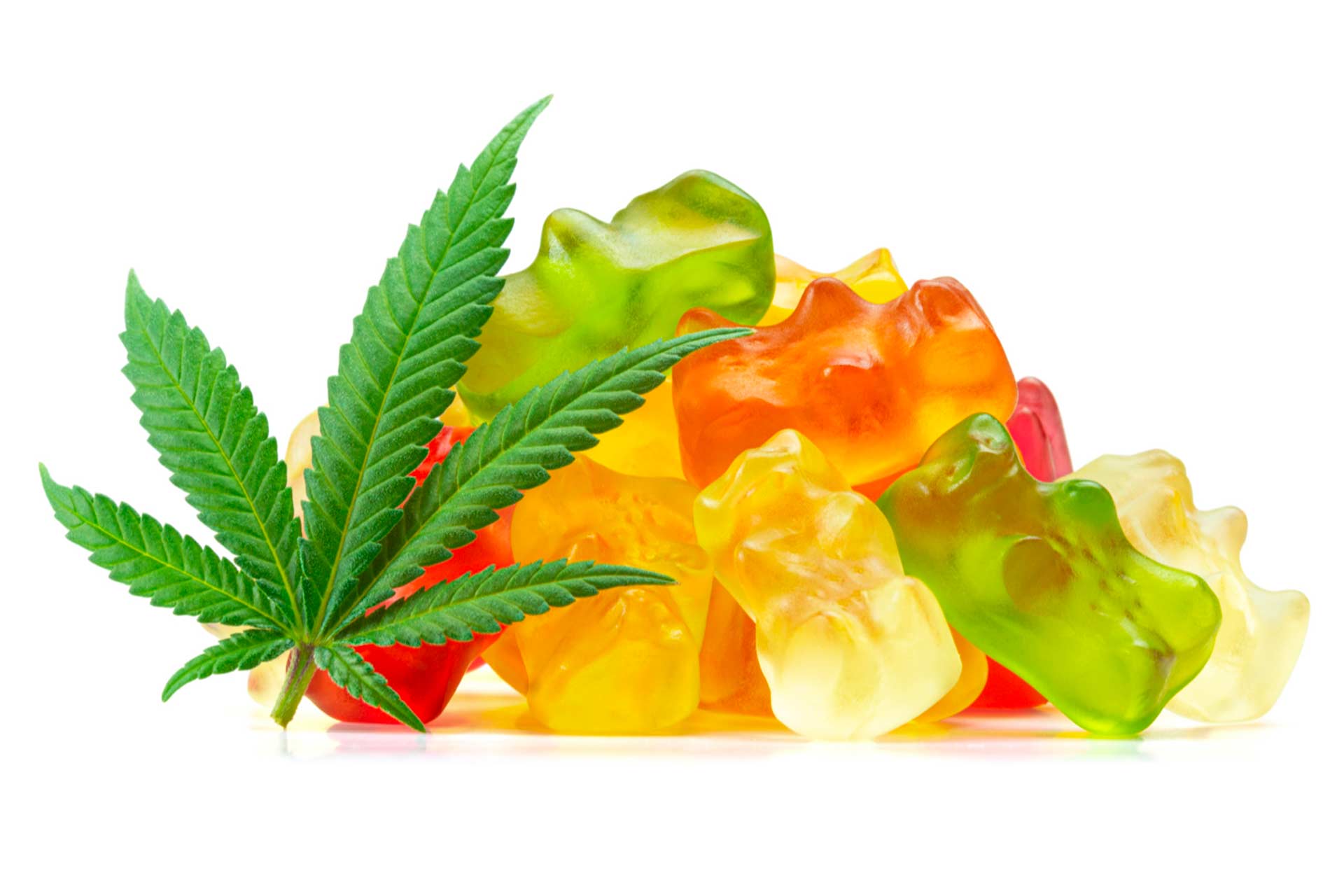 Colorful cannabis edible gummies stacked next to a cannabis leaf.