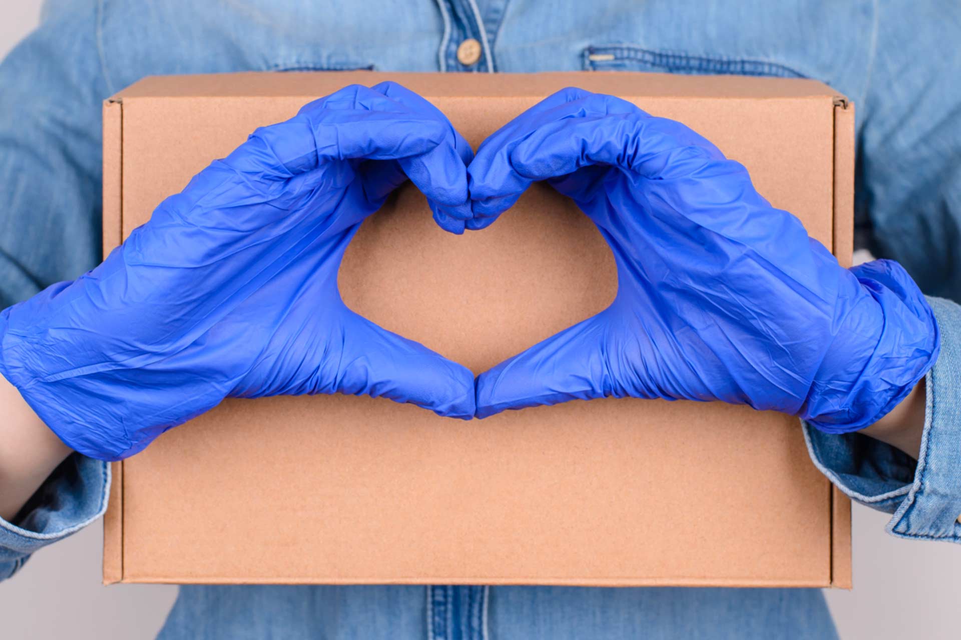 Hands covered by disposable blue nitrile gloves making a heart, in recognition of cannabis essential workers during COVID-19
