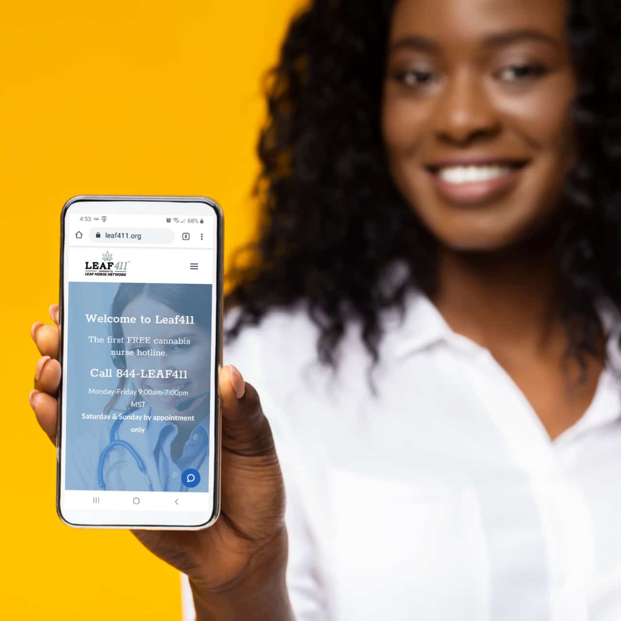 Black woman in white shirt smiling and holding out a smartphone with the Leaf411 website showing on the screen.
