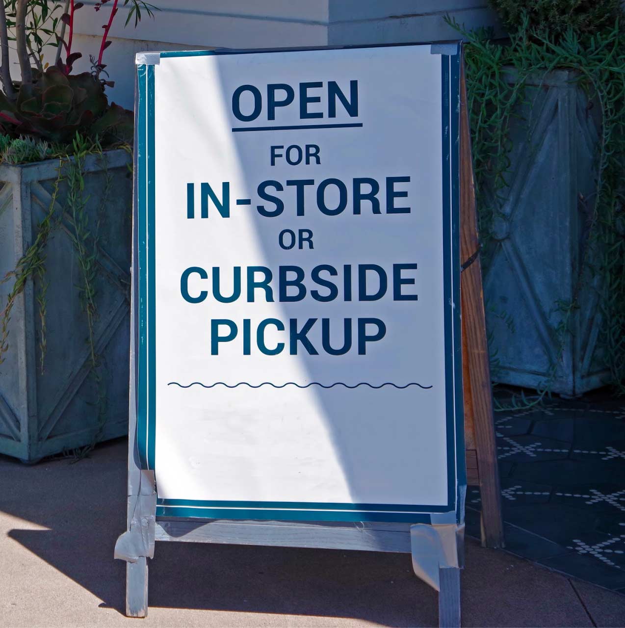 Sign outside shop saying, “Open for In-store or curbside pickup,” reflecting COVID-19 restrictions.