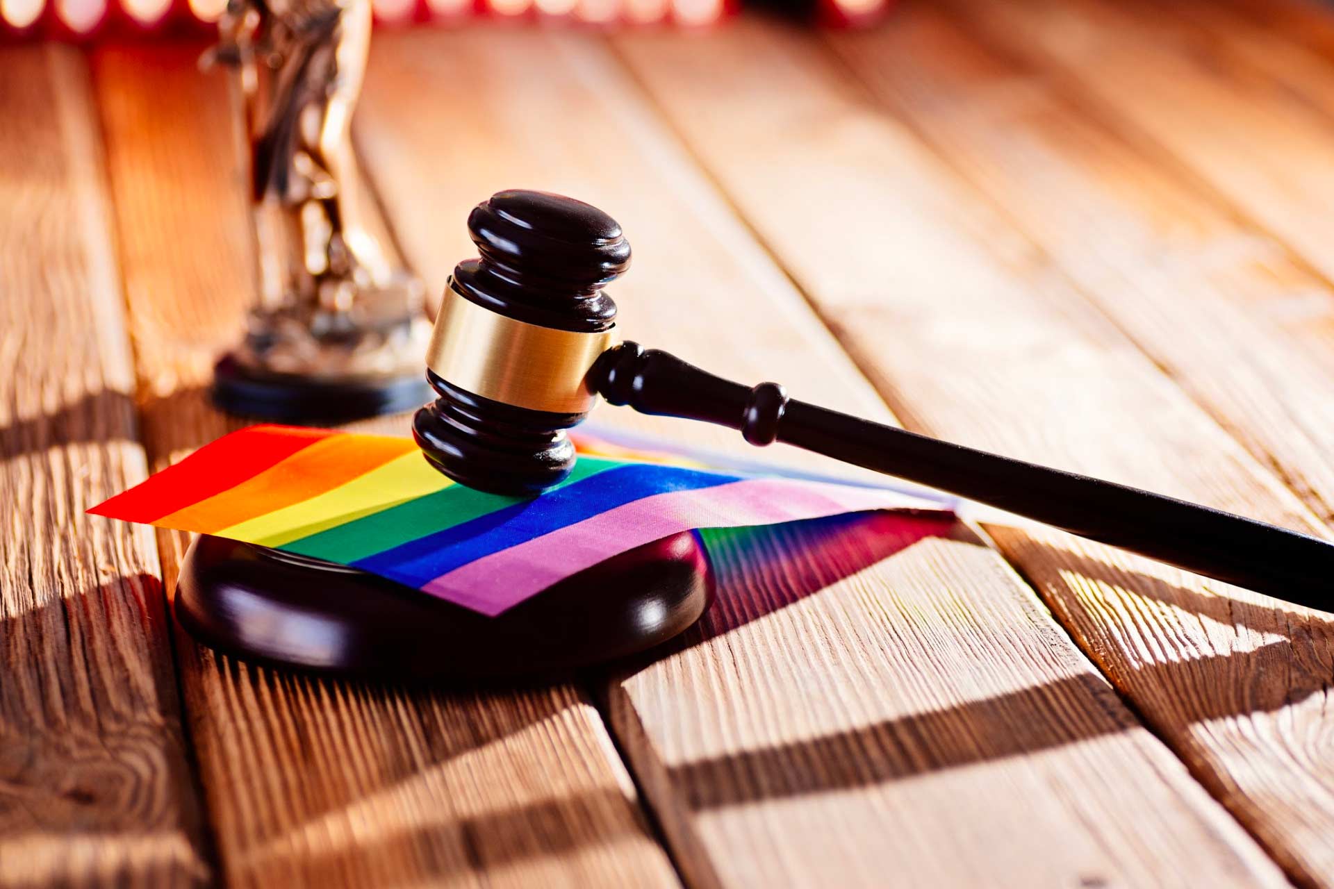 Court gavel resting on a rainbow flag, symbolizing the victories and challenges LGBTQ people face.