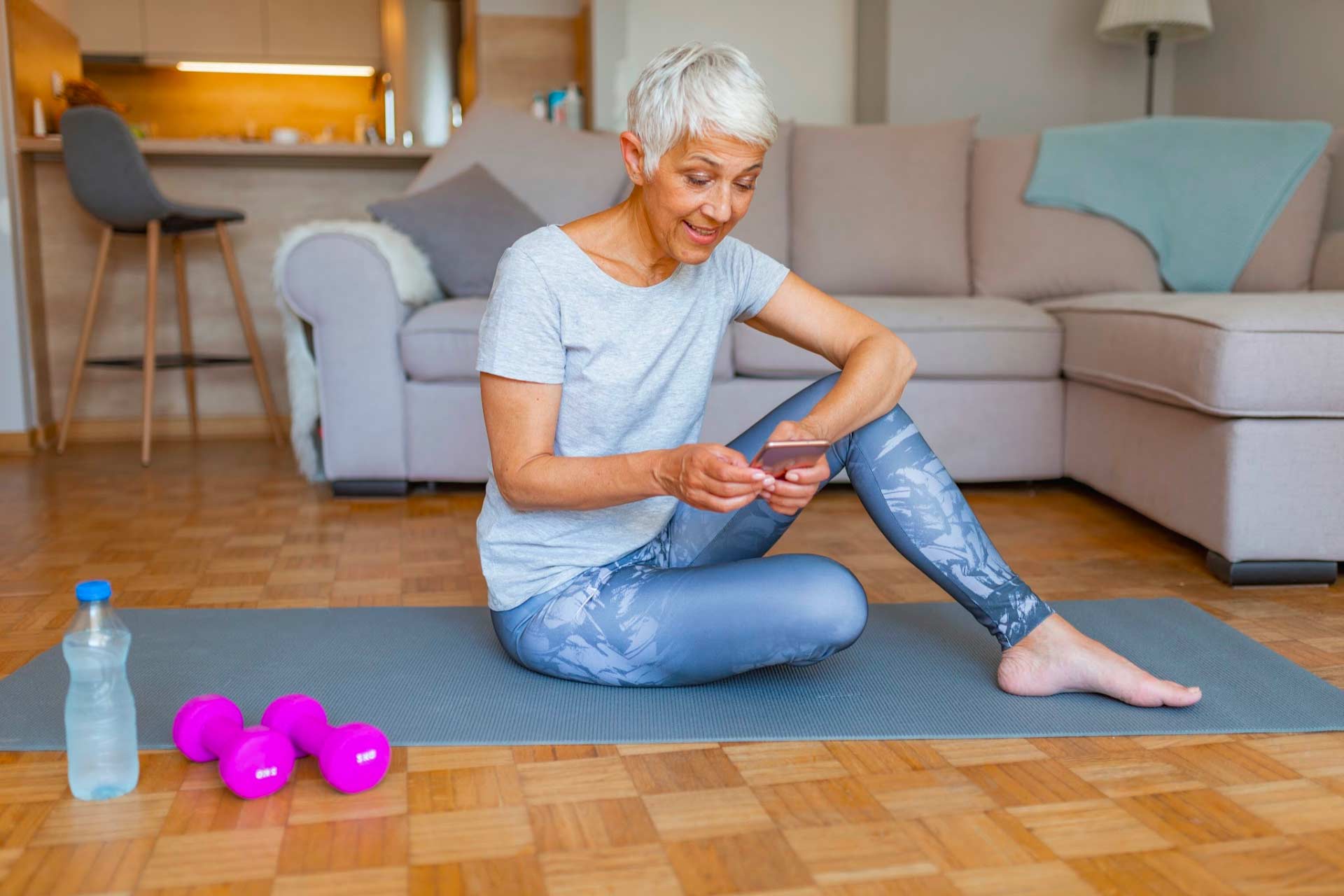 Healthy older white woman at home sitting on a yoga mat while calling Leaf411 with sleep questions.