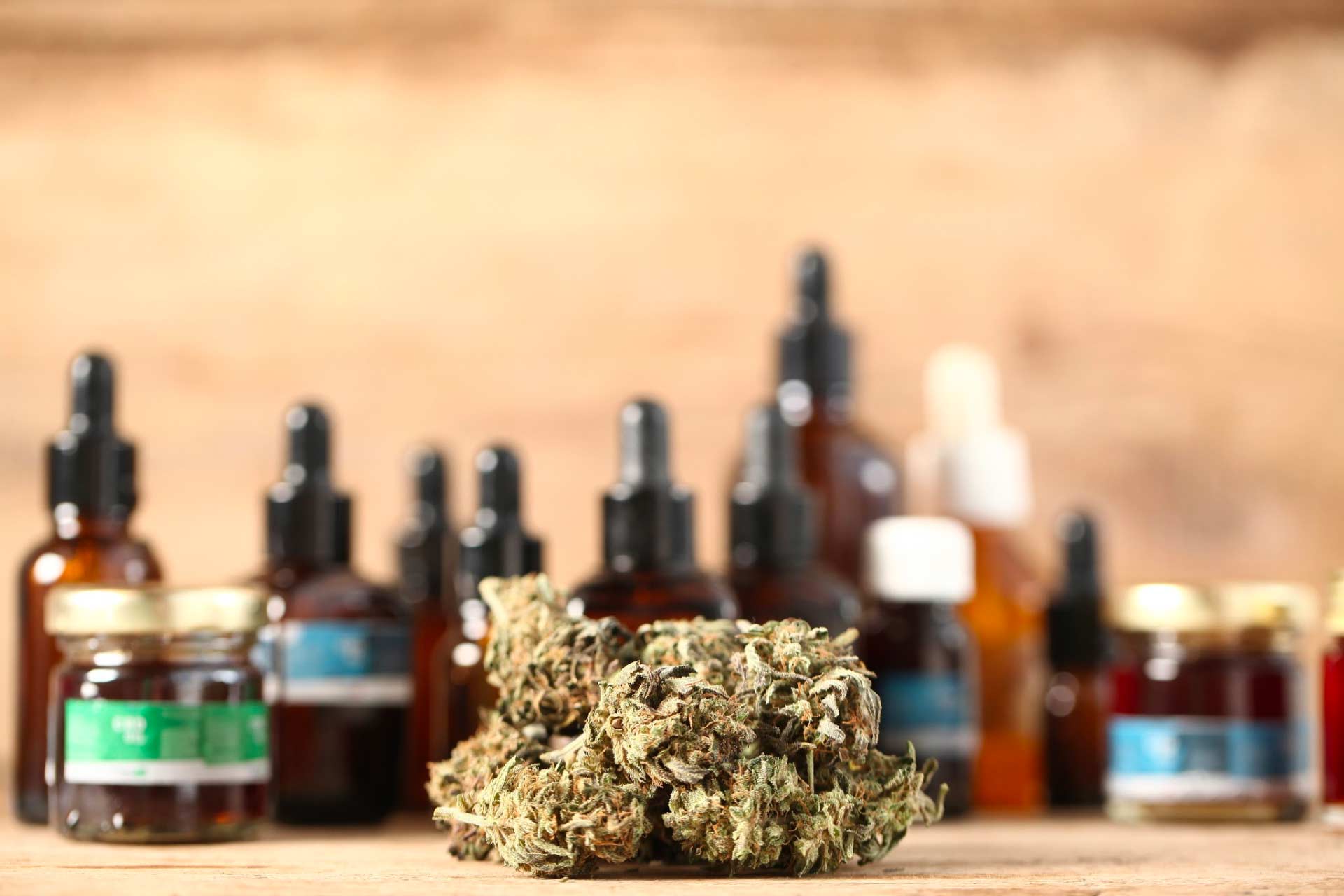 Various cannabis tinctures and other products, with cannabis flower (bud) in foreground.