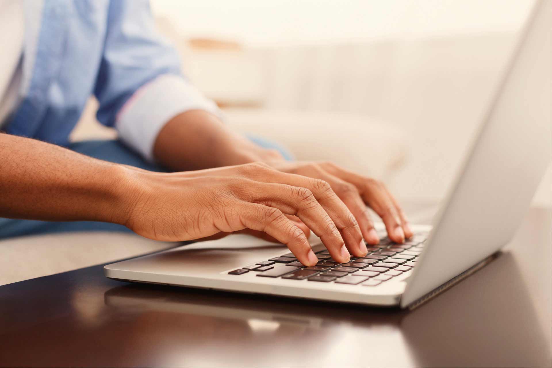 Close-up of hands on a laptop keyboard, as the person completes the online med card application.