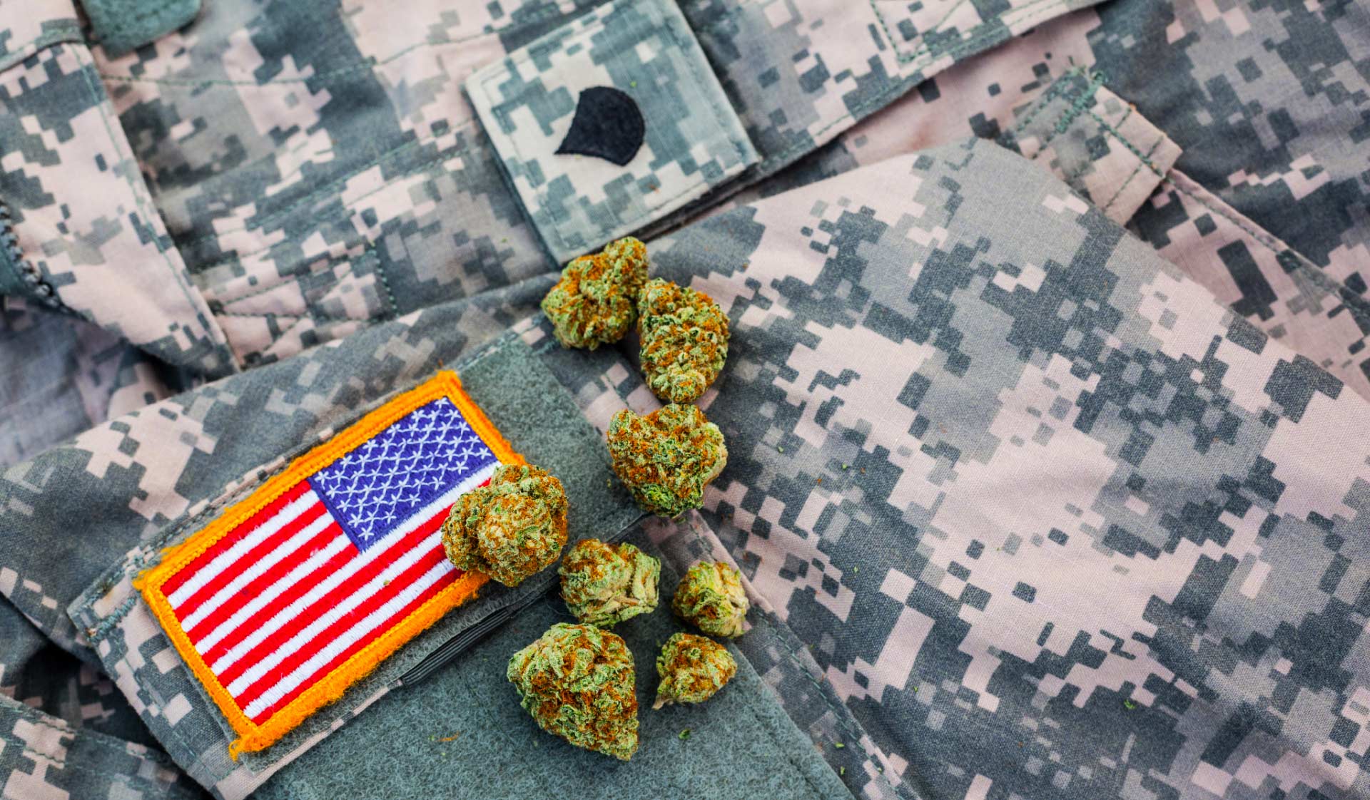 Close up of military field jacket and American flag patch with cannabis flower on top.