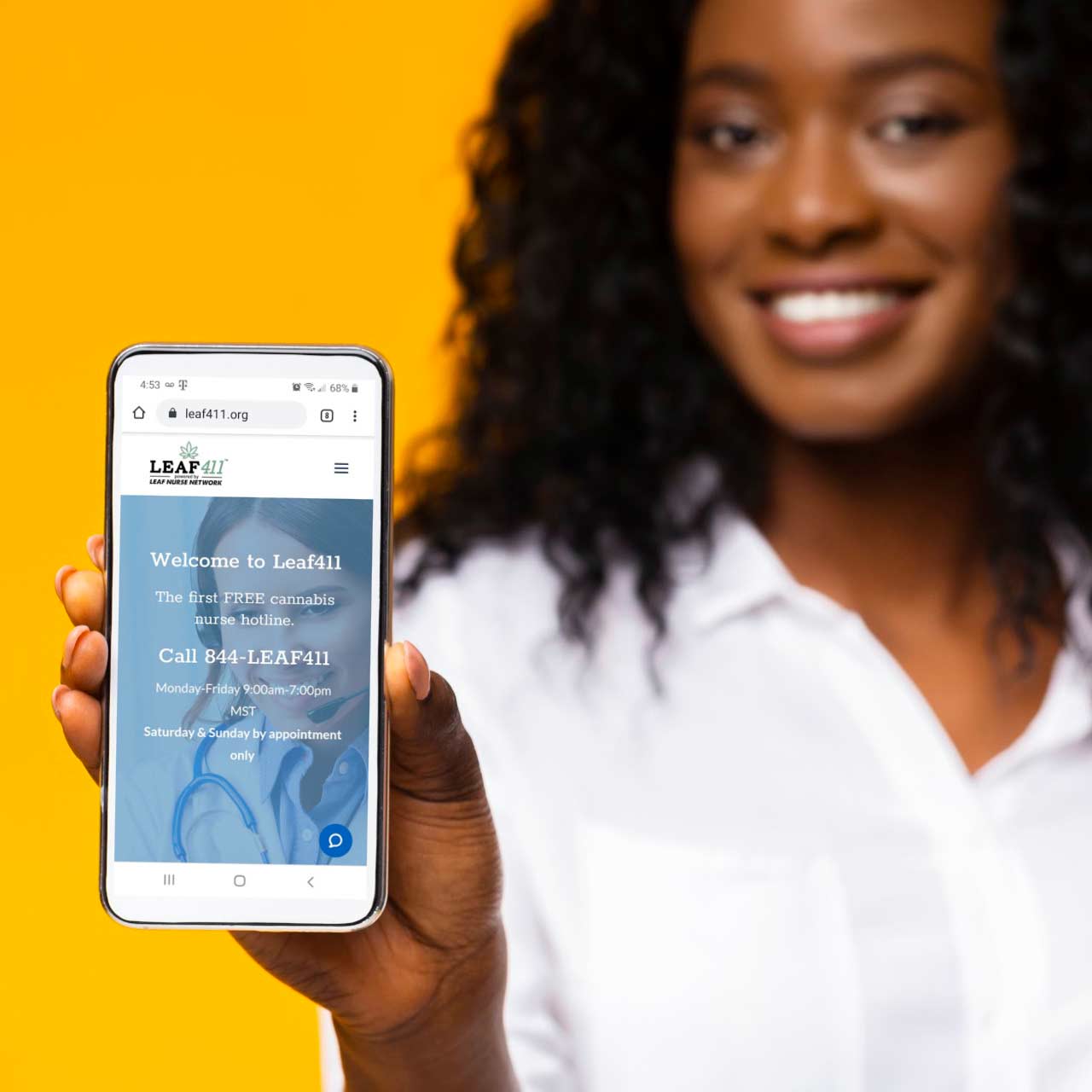 Smiling Black woman holding out smartphone with the Leaf411 cannabis nurse hotline homepage shown.