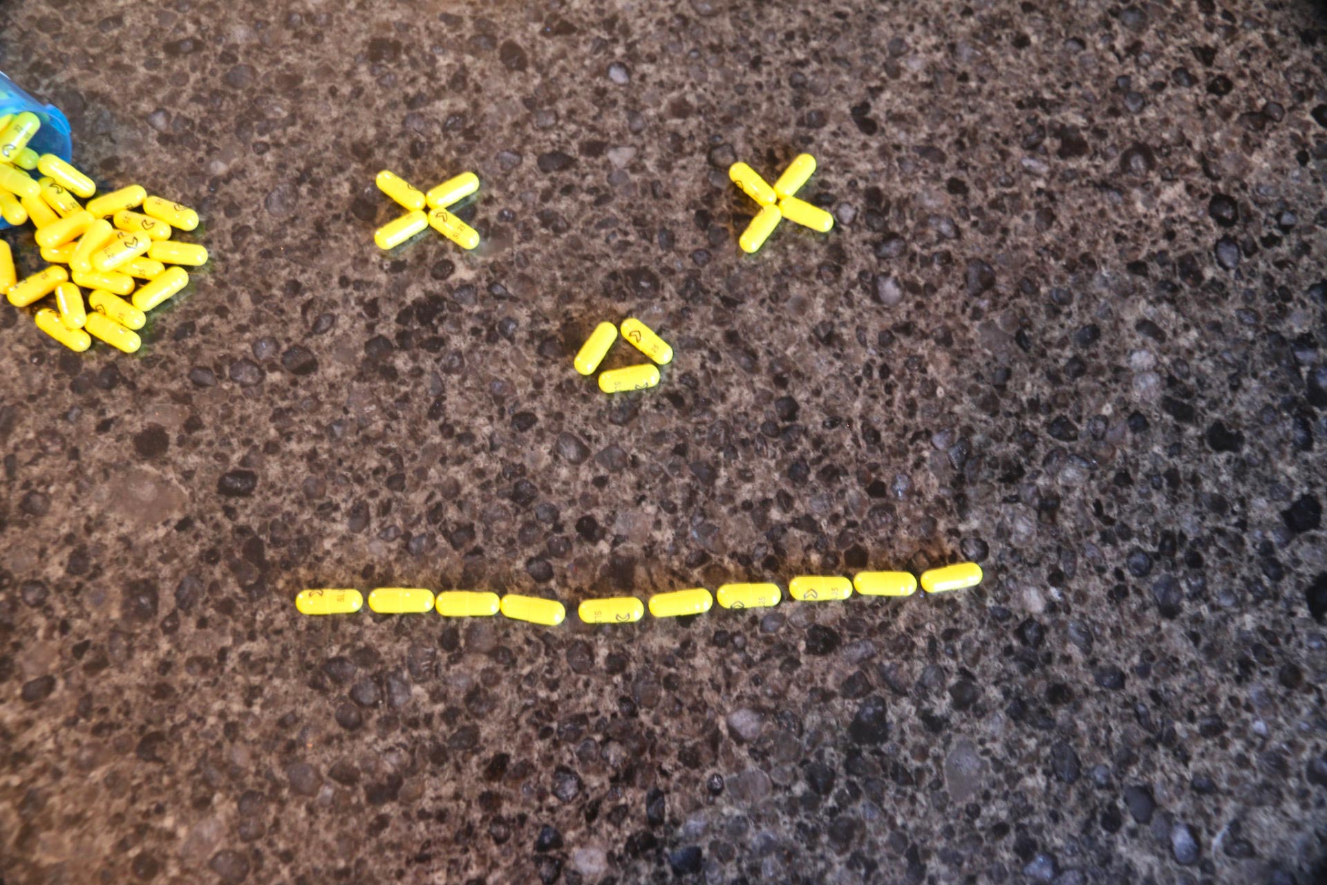 Pills laid out to make unsmiling face with “x” for eyes, the numbing effect of psychiatric meds