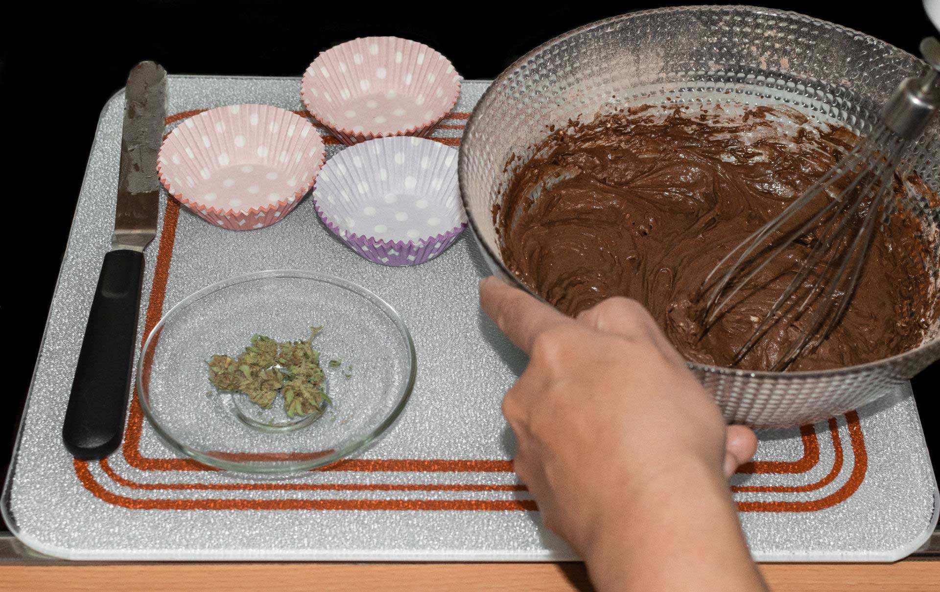 Making edibles, with cannabis shake in a small dish next to a mixing bowl with brownie batter.