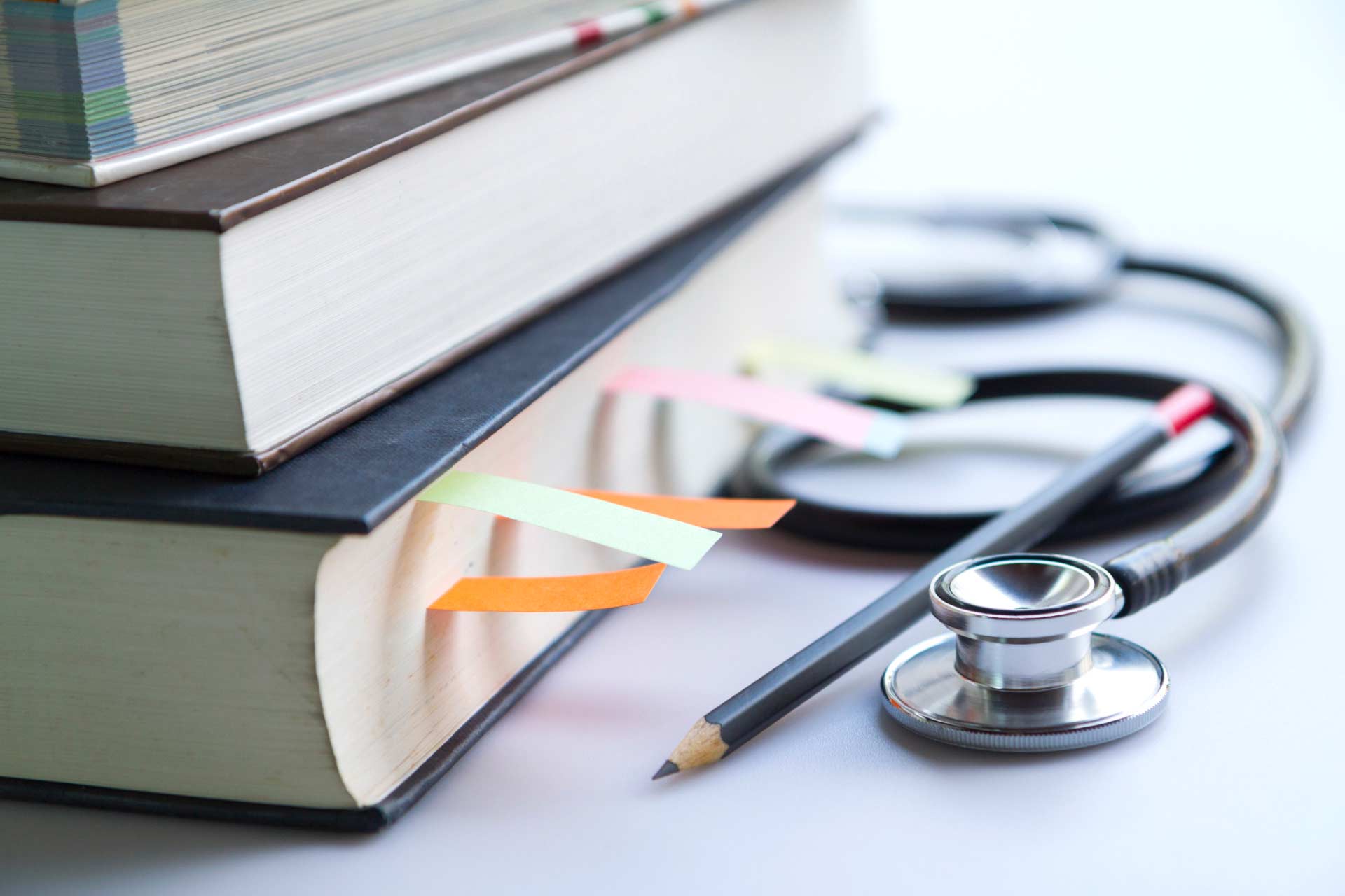 Stethoscope, pencil, and stack of medical textbooks on desk, representing cannabis nurse education