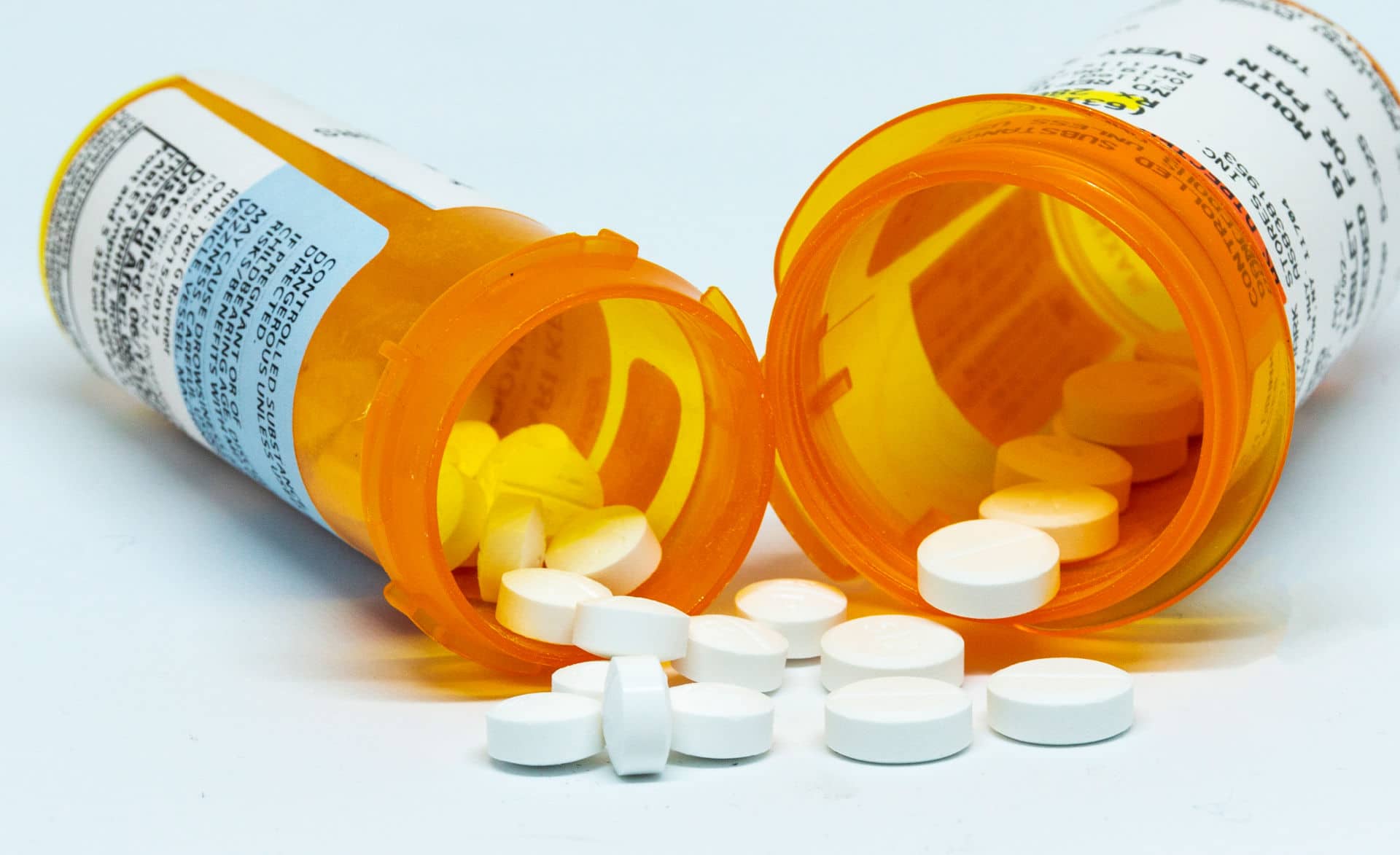 Prescription pain pills next to opioid prescription bottles.