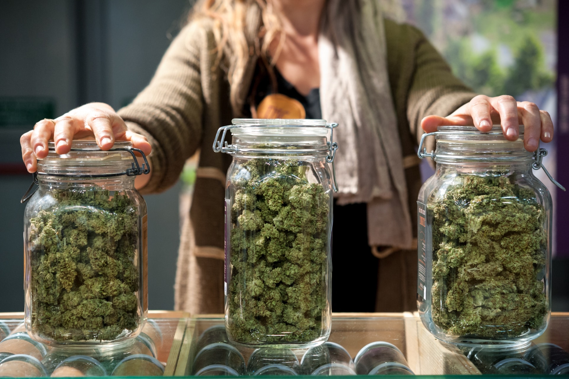 Cannabis flower strains displayed in glass jars at a dispensary.