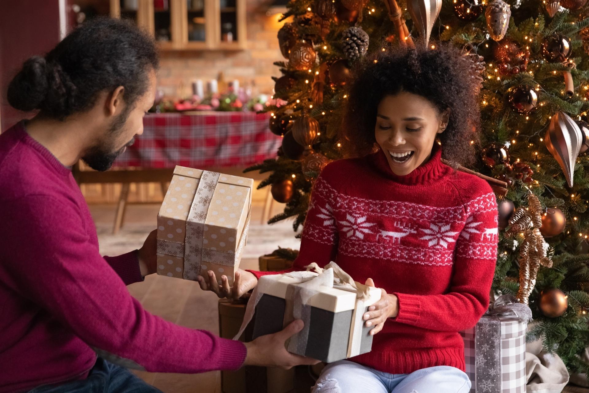 Leaf411’s 2021 Holiday Gift Guide: PHoto of a couple opening holiday gifts by a Christmas tree