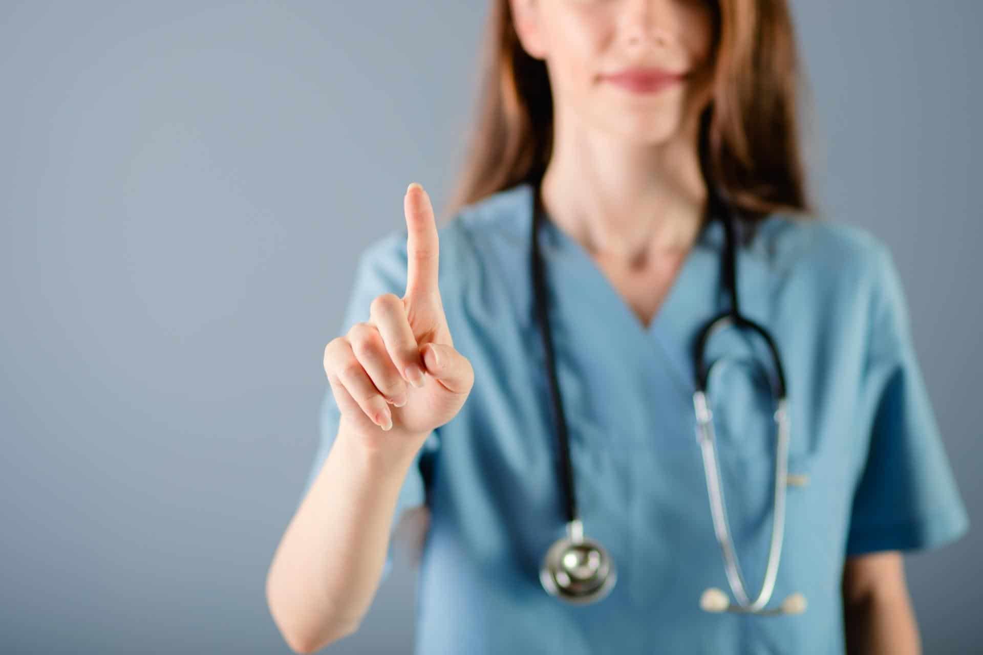 Nurse holding up index finger in a gesture that signifies helpfulness.