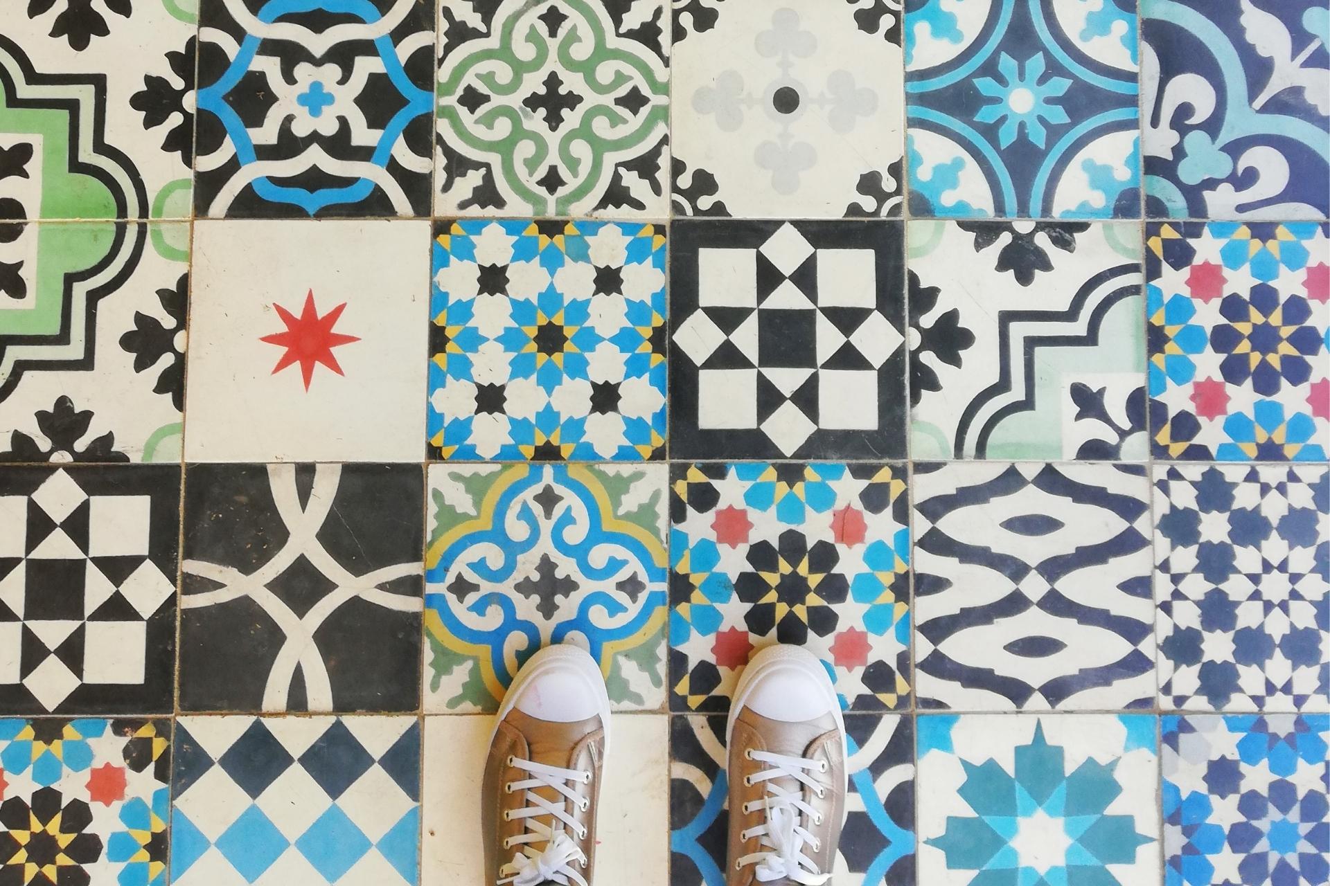 Feet standing on edge of colorful tile floor representing a wide range of cannabis options.